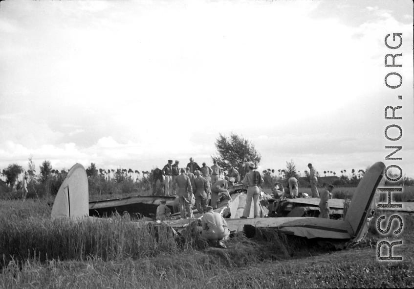 GIs inspect crashed and pancaked B-24 in a grainfield in China during WWII, between 1943-1945. 