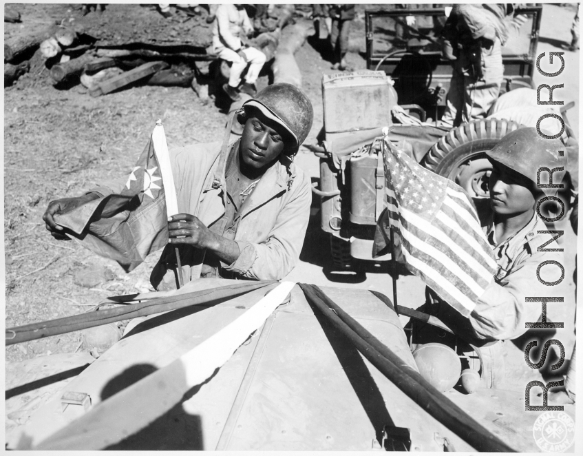 "A U.S. Army soldier and a Chinese soldier place the flag of their ally on the front of their jeep just before the first truck convoy in almost three years crossed the China border en route from Ledo, India, to Kunming, China, over the Stilwell road."