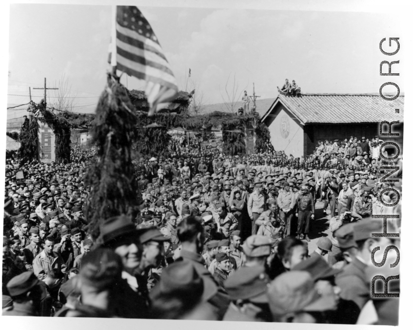 Burma Road dedication parade and ceremony in Kunming, China, on or around February 4, 1945, during WWII. Review of first convoy (or one of the first convoys) to reach China. Ranks of soldiers and civilians. Note movie camera filming on far right, and just below that, a couple of African-American officers.