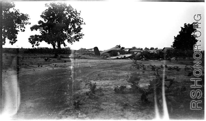 Wrecked B-25 Mitchell bomber on the ground in the CBI. The wreck was apparently at an air base, and probably on take-off, as the craft is sprayed with fire-retardant foam, and bombs are scattered about the wreck site. During WWII.