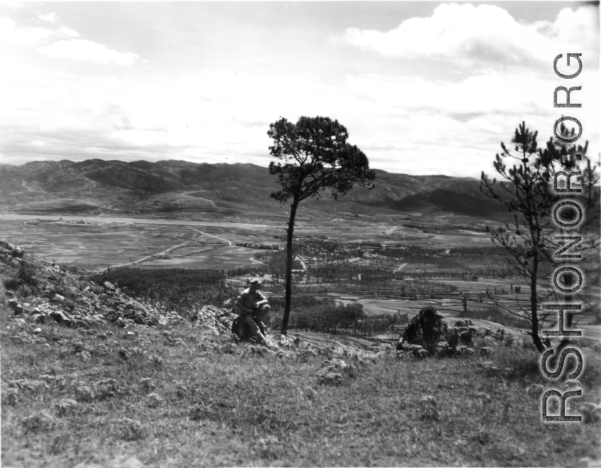 An American serviceman walking  on the hill above Yangkai air base, in Yunnan province, China, during WWII. Note the carbine rifle he carries for protection.