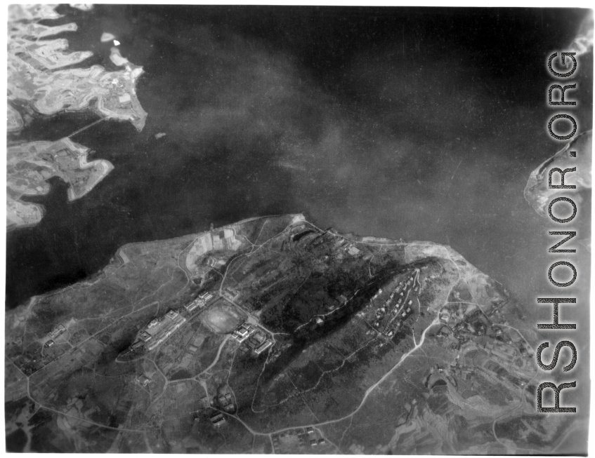 Aerial view of a large organized campus with large ornate buildings, an athletic track, housing, etc., in either SW China, Burma, or French Indochina, in the CBI, during WWII. Is this a university of some kind?