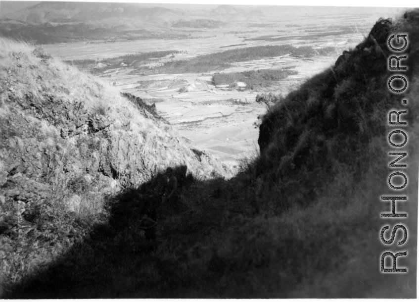 An American serviceman (partially hidden in shadow) walking on the hill above Yangkai air base, in Yunnan province, China, during WWII. He is being escorted by a local boy.