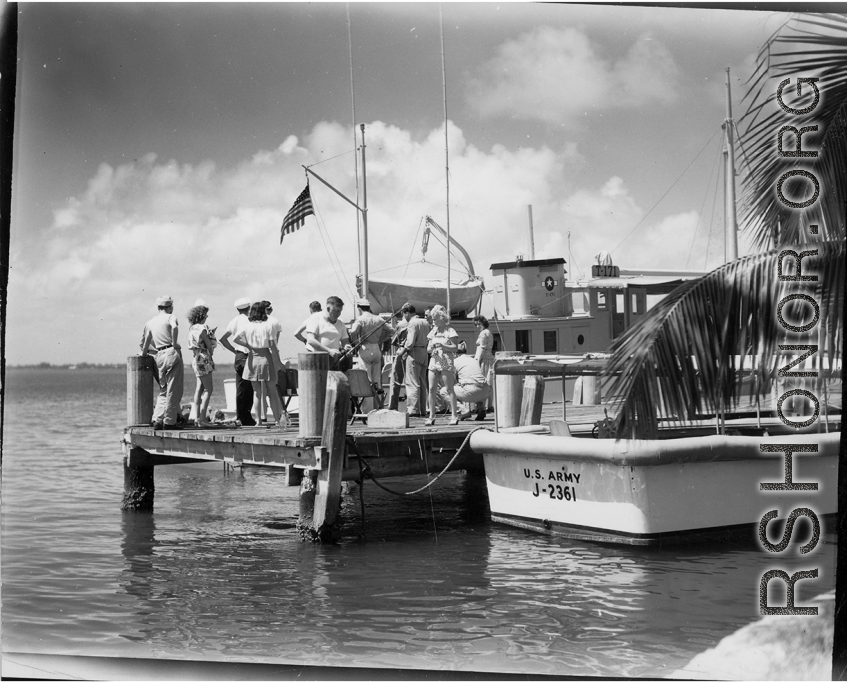 A GIs and civilians play at the waterside, likely in Florida, during WWII. Note U. S. Army boats #J-2361 & #T-171.