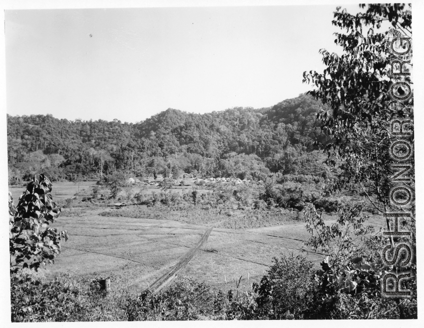 A tent camp in the forest in the distance, of the 797th Engineer Forestry Company, in Burma.  During WWII.