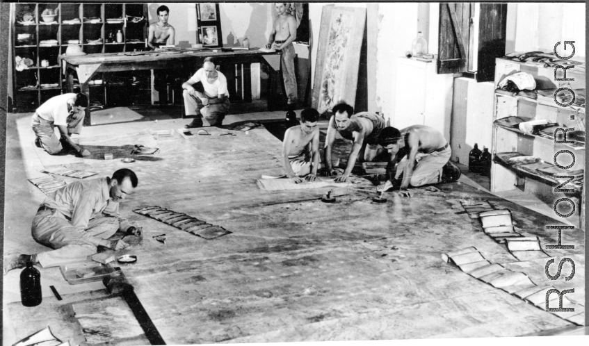 Organizing images on large panels on the floor at photo lab of the 24th Mapping Squadron--cutting and pasting numerous high-resolution aerial images together onto a board to create a wide view.