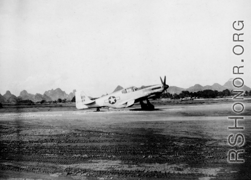 A P-51 fighter at a base in China during WWII. Tail number #271 37124. Although David Axelrod spent at least part of his time at Luliang, the karst formations in the background do not resemble the mountains of Luliang, and this is morel likely a base in Guangxi, such as Liuzhou, etc.