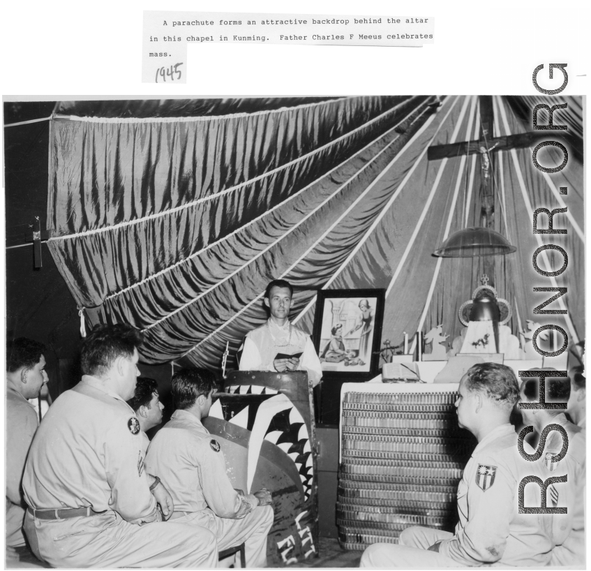 A parachute forms a backdrop in this Chapel in Kunming in 1945. Father Charles F. Meeus celebrates mass.  The Father's pulpit is the cowling for the P-40K "Little Flower" flown by Ray Kaiser (25th FS). "Little Flower" was St Therese from Lisieux, France. (Thanks JBarbaud)  Notice the corrugated metal making up the lower area of the alter, also likely parts from aircraft or packaging munitions.