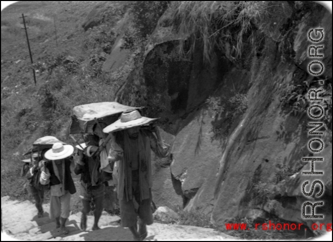 Bearers carry people in sedan chairs up mountain in northern China during WWII.