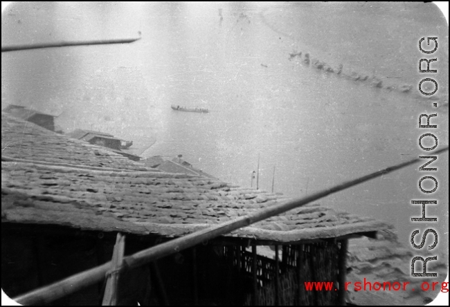 Houses clustered on the Yellow River during WWII, possibly in or near Lanzhou, and a boat in the river.