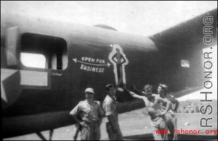 Men pose next to artwork of the tail of B-24 "Open For Business" of the 308th Bombardment Group.