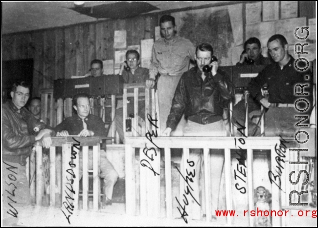 Scene of the workings of the Fighter Control Squadron, 51st Fighter Group, 14th Air Force, as the team works to plot and intercept Japanese planes. Left to right: Lt. Raymond E. Wilson, Capt. Spencer Lansdown, Capt. Dale D. Desper, Col. Louis R. Hughes, Jr., Capt. Thomas E. Stenton, "Buttons" the puppy, and Capt. Glade C. Burton.