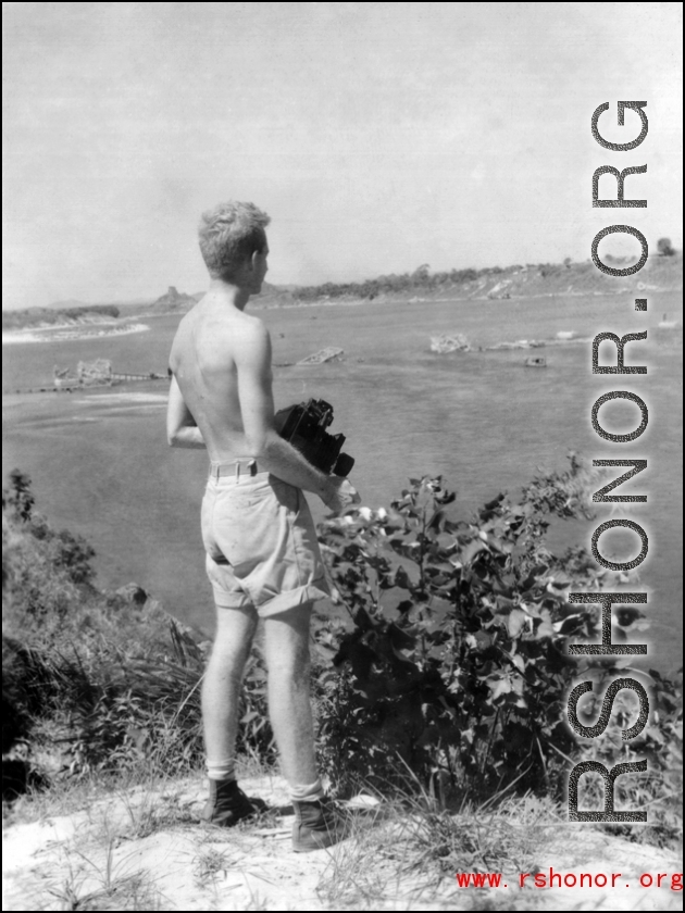 Robert Riese, camera in hand, looks over destroyed railway bridge in Liuzhou, in 1945, during WWII.