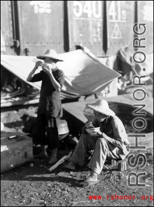 Chinese refugees take a meal at the train station in Liuzhou during WWII, in the fall of 1944.
