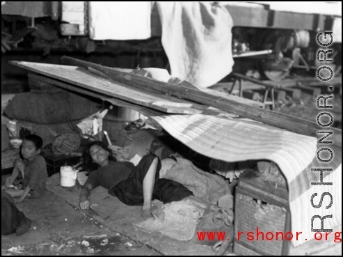 A Chinese refugee resting and hiding from the heat near a train at Liuzhou during the evacuation in Guangxi during the fall of 1944. 