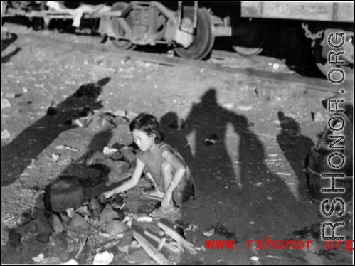 Chinese refugee--a young girl in this case--tends a cooking fire to boil water next to the train tracks in Liuzhou during WWII, in the fall of 1944, as the Japanese advanced during the Ichigo campaign.
