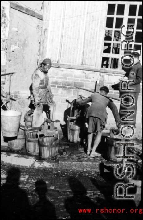 Town people in China get water in wooden buckets and shoulder poles during WWII.
