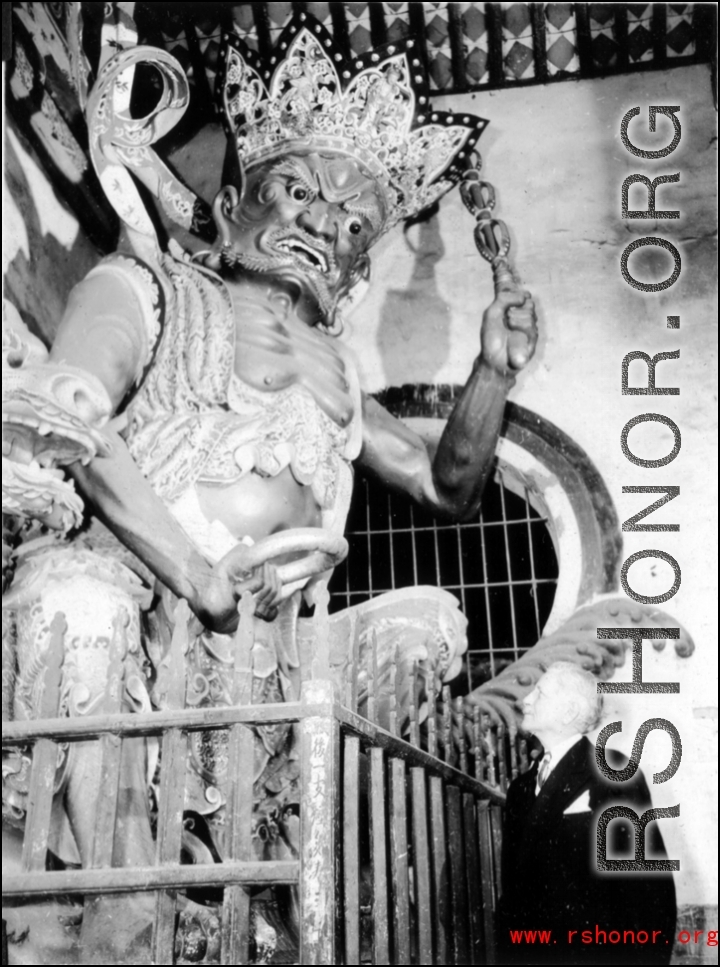 Suited westerner observed door guard at Buddhist temple in China during WWII.