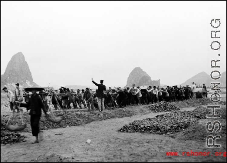 Chinese workers pulling a large roller at a base  in Guangxi province (probably Liuzhou, but maybe Guilin), China.