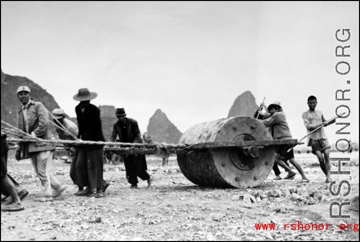 Chinese workers pulling a large roller at a base  in Guangxi province (probably Liuzhou, but maybe Guilin), China. 