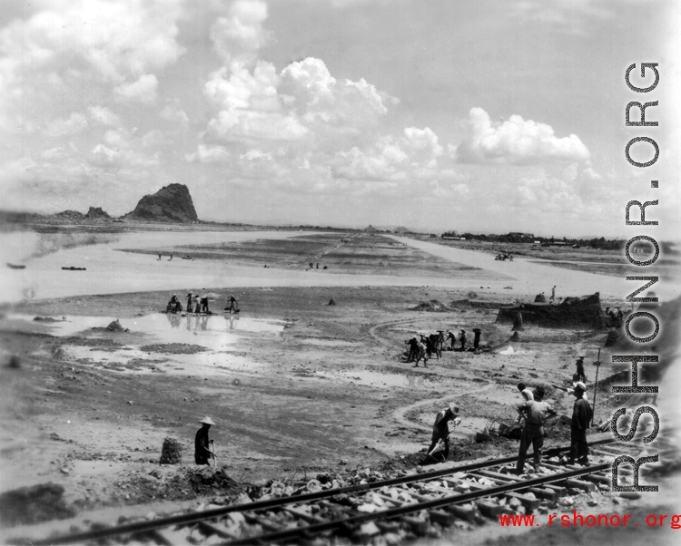 An airstrip under construction near a railroad, in a region of karst formations.  This is almost certainly Liuzhou, in Guangxi province.