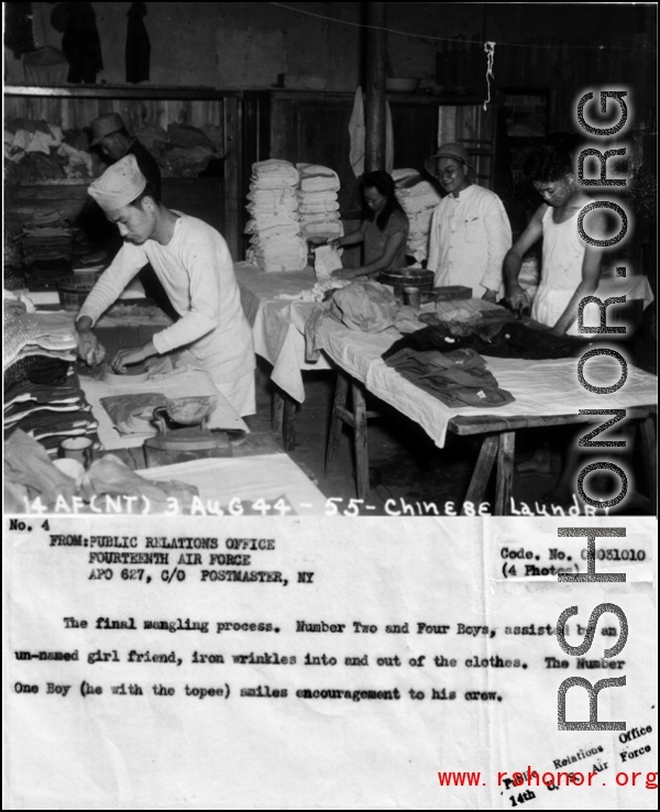 APO 627.  The final mangling process.  Number and Four Boys, assisted by an un-named girlfriend, iron wrinkles into and out of the clothes.  The Number One Boy (he with the topee) smiles encouragement to his crew.  From the U.S. Government sources.