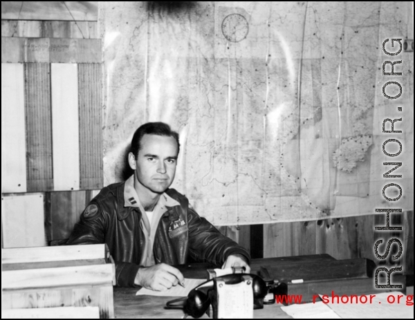 An American soldier with "Flanagan" (花纳根）on his jacket in the CBI. Notice the "491st Bomb Squadron daily status" on the wall behind him.  This is a photo of Captain James Flanagan who was the operations officer of the 491st Bomb Squadron. This photo was taken probably at Yangkai Airbase in late 1944. Please see: http://www.usaaf-in-cbi.com/ for additional information. (Thanks to sds)  From the collection of Wozniak, combat photographer for the 491st Bomb Squadron, in the CBI.