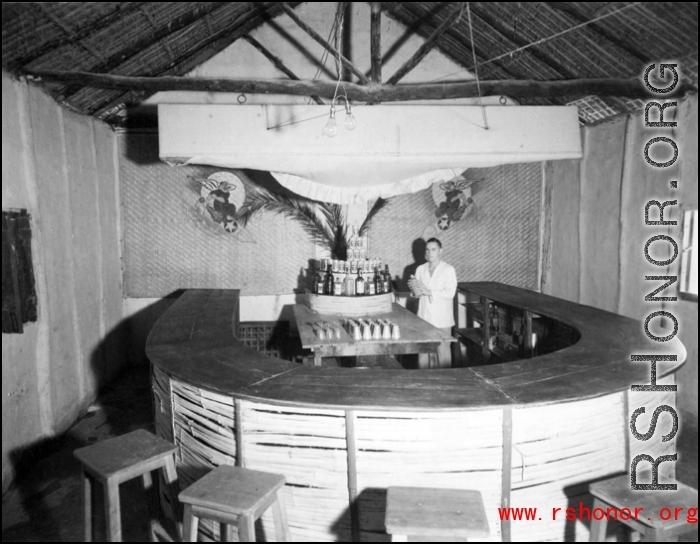 'The bar of the 491st Bombardment Squadron Officers' Club at Chakulia Air Base, India.  Notice the "Bomb Jockeys" emblems on the rear wall. The early insigne was not officially sanctioned. In the latter part of 1943 a new insigne, "Ringer Squadron", was accepted and became the 'official' emblem until replaced in 1957.