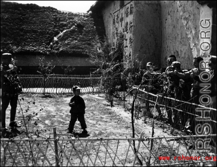 American and Chinese servicemen exchanging a "Ding Hao" thumbs up with a young Chinese boy the CBI. 