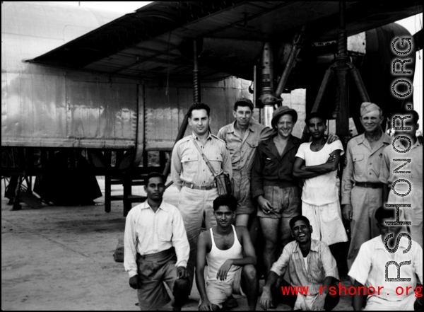 American and Indian service crew members pose for the camera in front of a B-24 up on jack and undergoing maintenance. 61st Air Service Group.