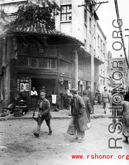 Local people in Kunming, Yunnan province, China: A busy street corner and food shop.