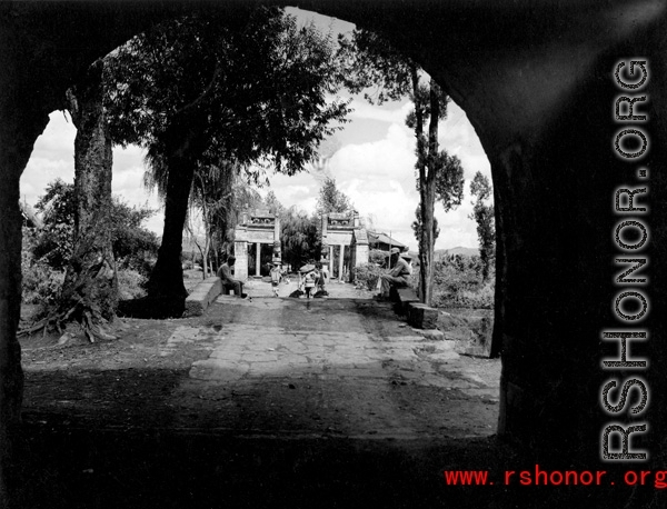 Looking at a bridge through a city gate onto a small bridge over a canal, in Yunnan province, China. During WWII.