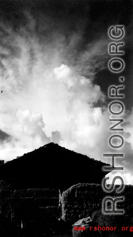 A village near Yangkai, Yunnan province, China: Bright clouds high in the sky. During WWII.