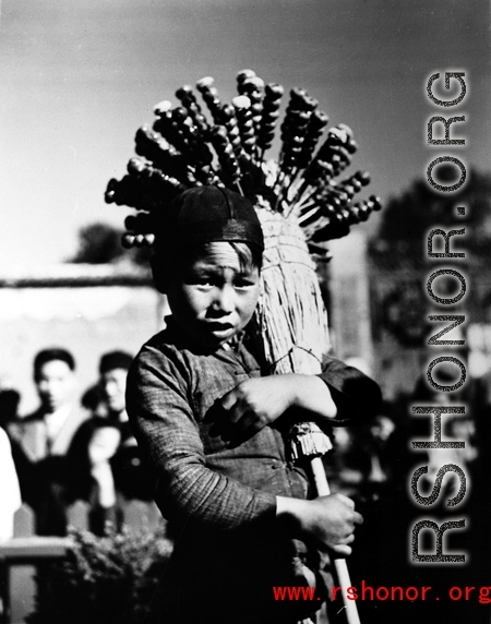 Local people in China, including a young candied fruit seller selling candied haws fruit on bamboo skewers.  From the collection of Eugene T. Wozniak.