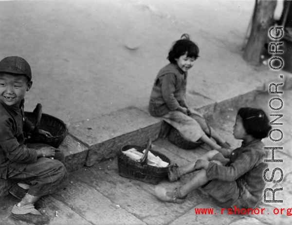 Local kids in China during WWII play on street curb.  From the collection of Eugene T. Wozniak.