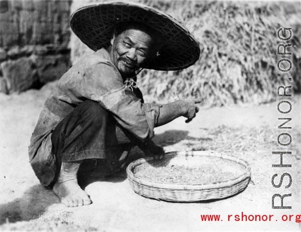 Local people in China: A farmer picks through grain to clean it.