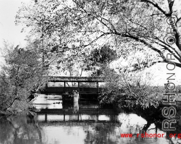 Local scenery in Yunnan province, China, during WWII: A covered pedestrian bridge over a canal.  From the collection of Eugene T. Wozniak.