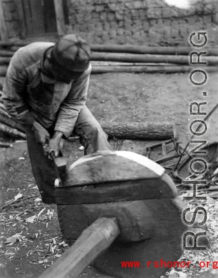 A craftsman repairing a wooden wheel in WWII China. 