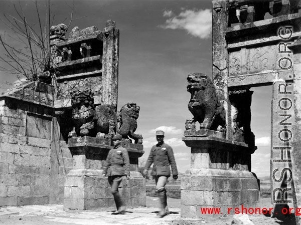 Two Chinese soldiers walk through a ceremonial gate in Yunnan province during WWII.