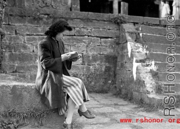 A woman in a maternity dress in a village in Yunnan during WWII. She is likely to be wife of a Nationalist officer, billeted to live in the village, rather than a woman who grew up in the village.