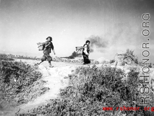 Fleeing women look back over their shoulders at a Japanese air raid on Kunming city in Yunnan province, China, during WWII.