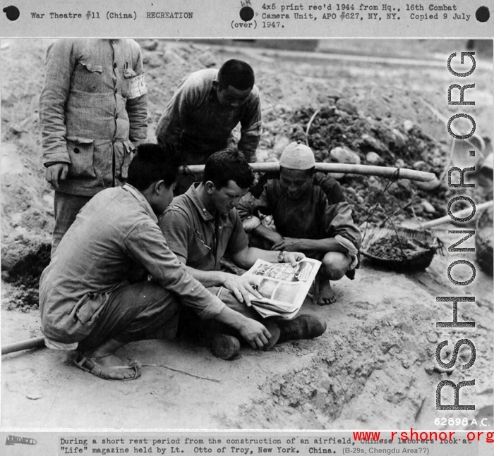 During a short rest period from the construction of an airfield (maybe at Chengdu), Chinese laborers look at "Life" magazine held by Lt. Otto of Troy, New York, in China during WWII.