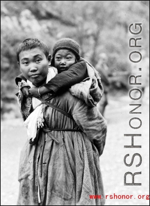 Refugee child being carried while fleeing around either Liuzhou or Guilin during the evacuation before the Japanese Ichigo advance in 1944, in Guangxi province.