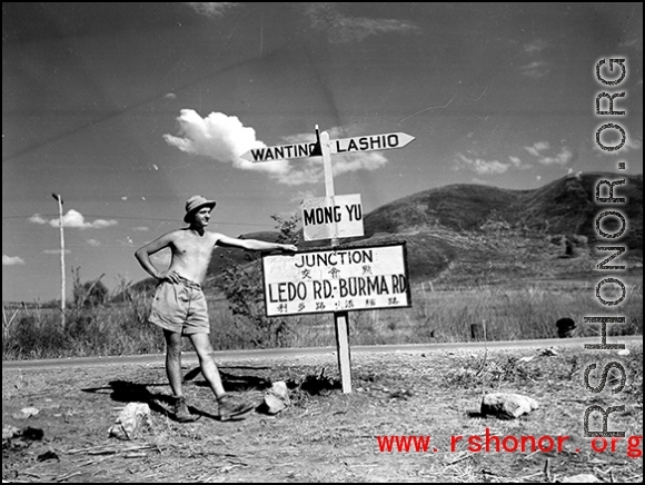 GI leans against sign at junction of Ledo Road and the Burma Road, during WWII.