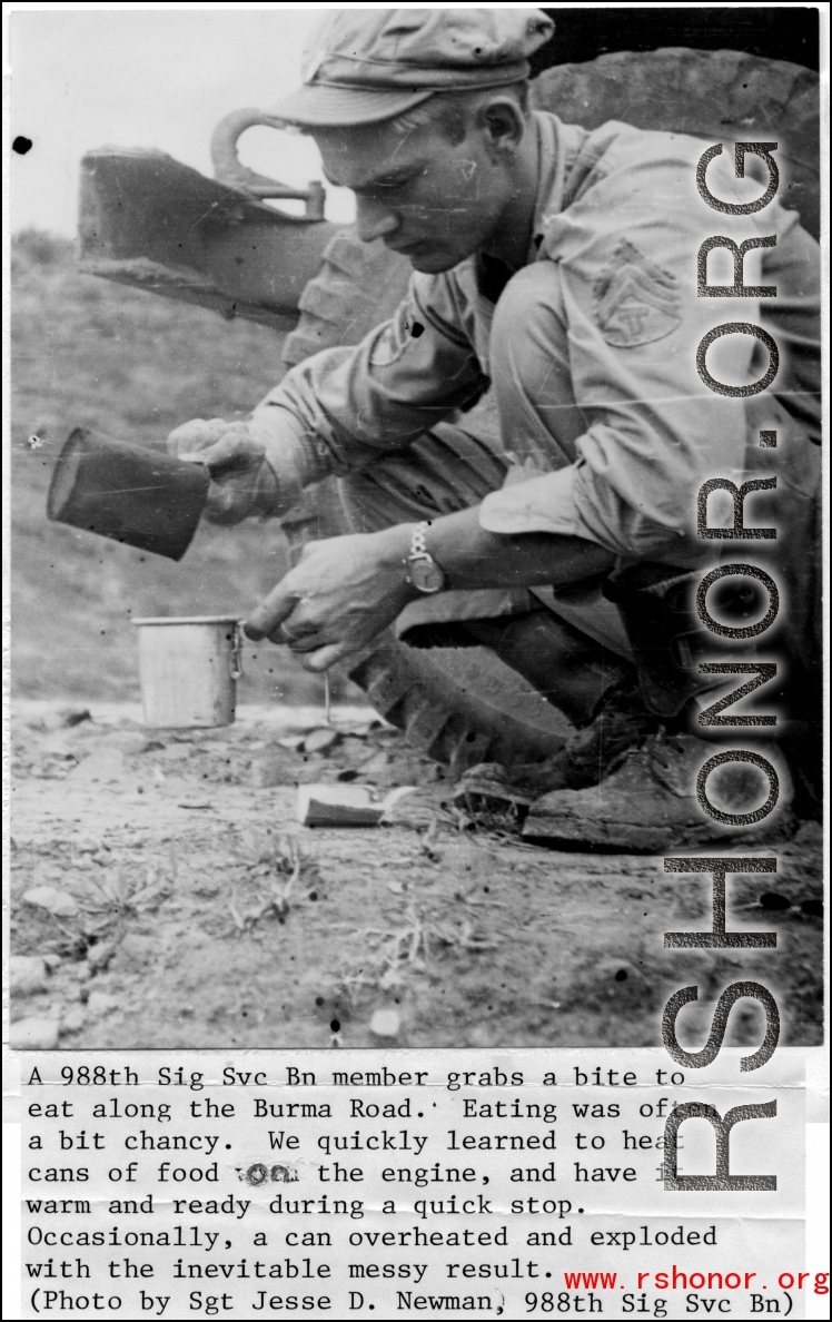 Member of the 988th Signal Service Battalion grabs a bite to eat along the Burma Road. "We quickly learned to heat cans of food on the engine, and have it warm and ready for a quick stop."