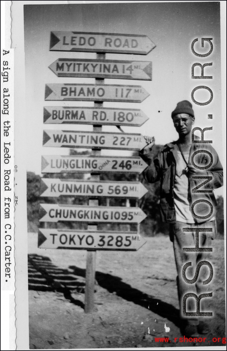 An American GI poses next to a heavily loaded sign post along the Ledo Road during WWII.  Photo from C. C. Carter.