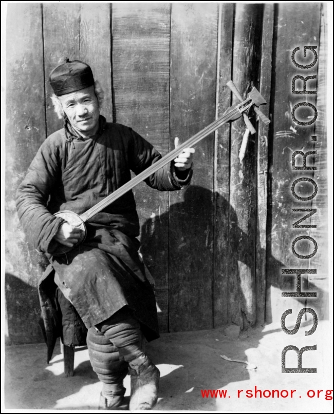 A man plays a three-string Chinese lute ( 三弦) in the CBI during WWII. 