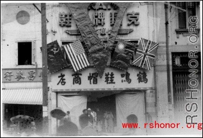 Victory "V" over shoe store in China at the end of the war, with the four flags of the Allies.