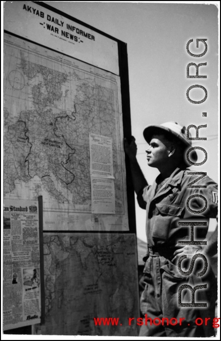 A GI reads about the war on a news board in Akyab.