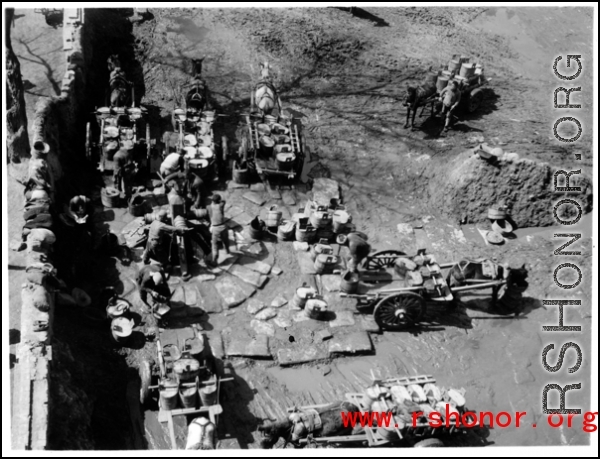 Chinese men with carts collect water at a large local well, and draw water for delivery, probably in northern China.